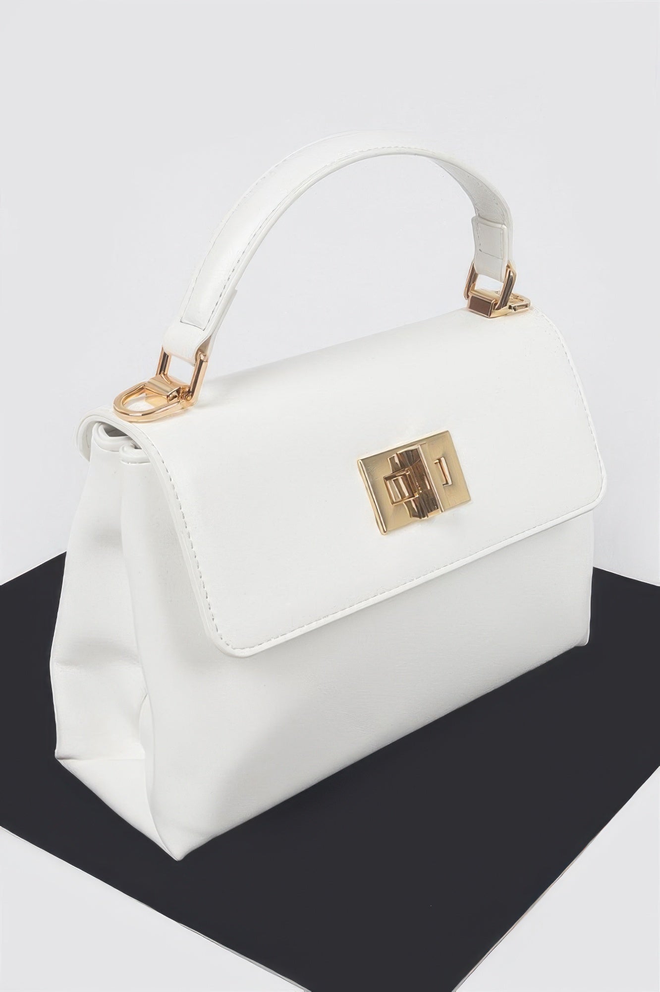 White faux leather flap bag with gold front clasp and curved top handle