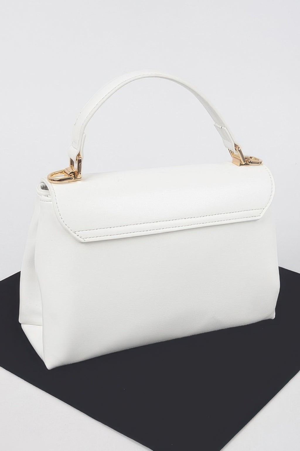 White faux leather flap bag with gold hardware and side profile stitching