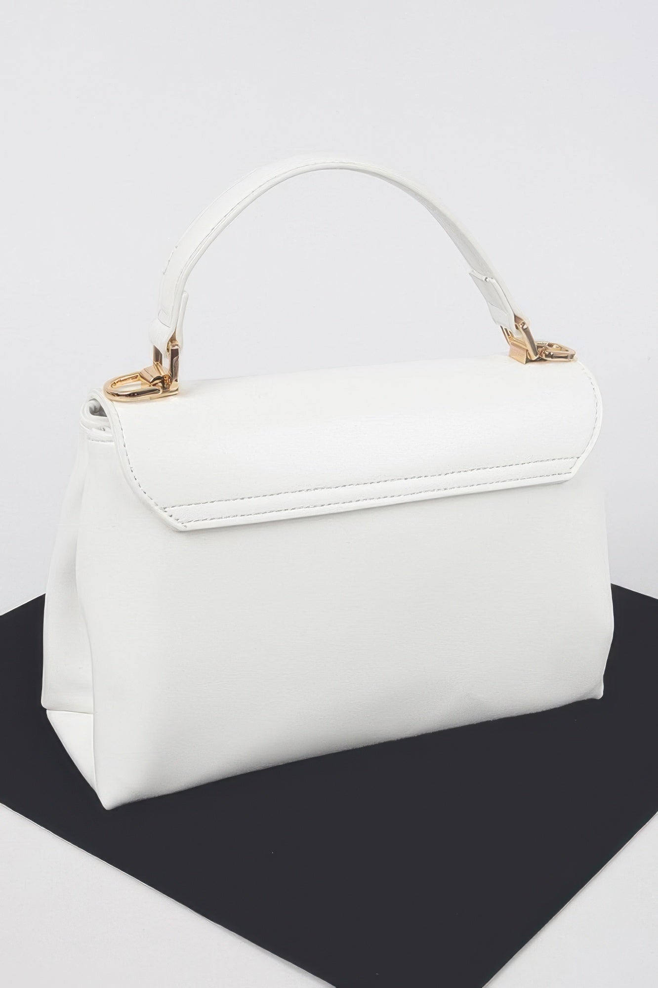 White faux leather flap bag with gold hardware and side profile stitching