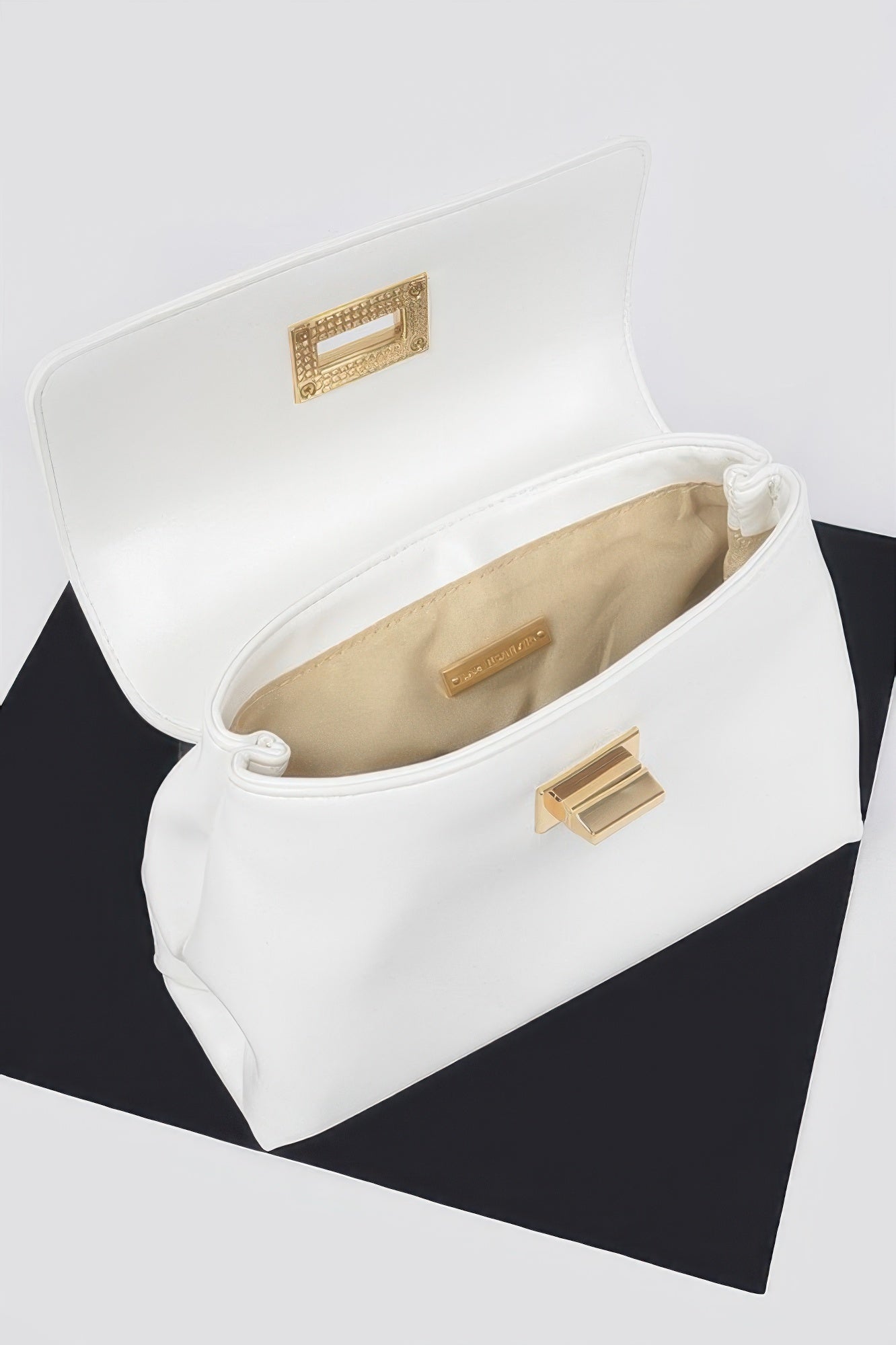 White faux leather flap bag open view with beige lining and gold clasp