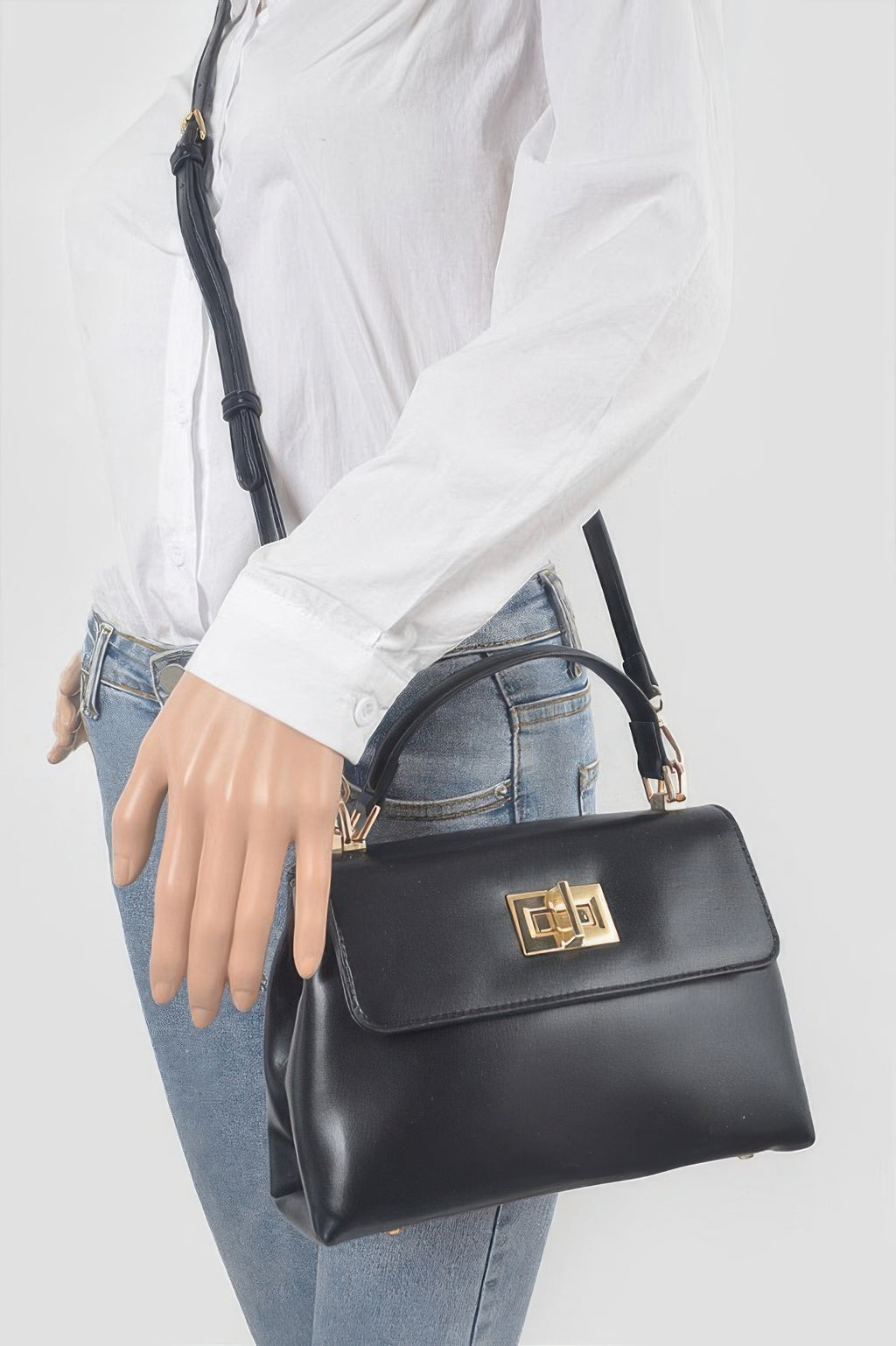 Black faux leather flap bag with gold square clasp, top handle, and shoulder strap