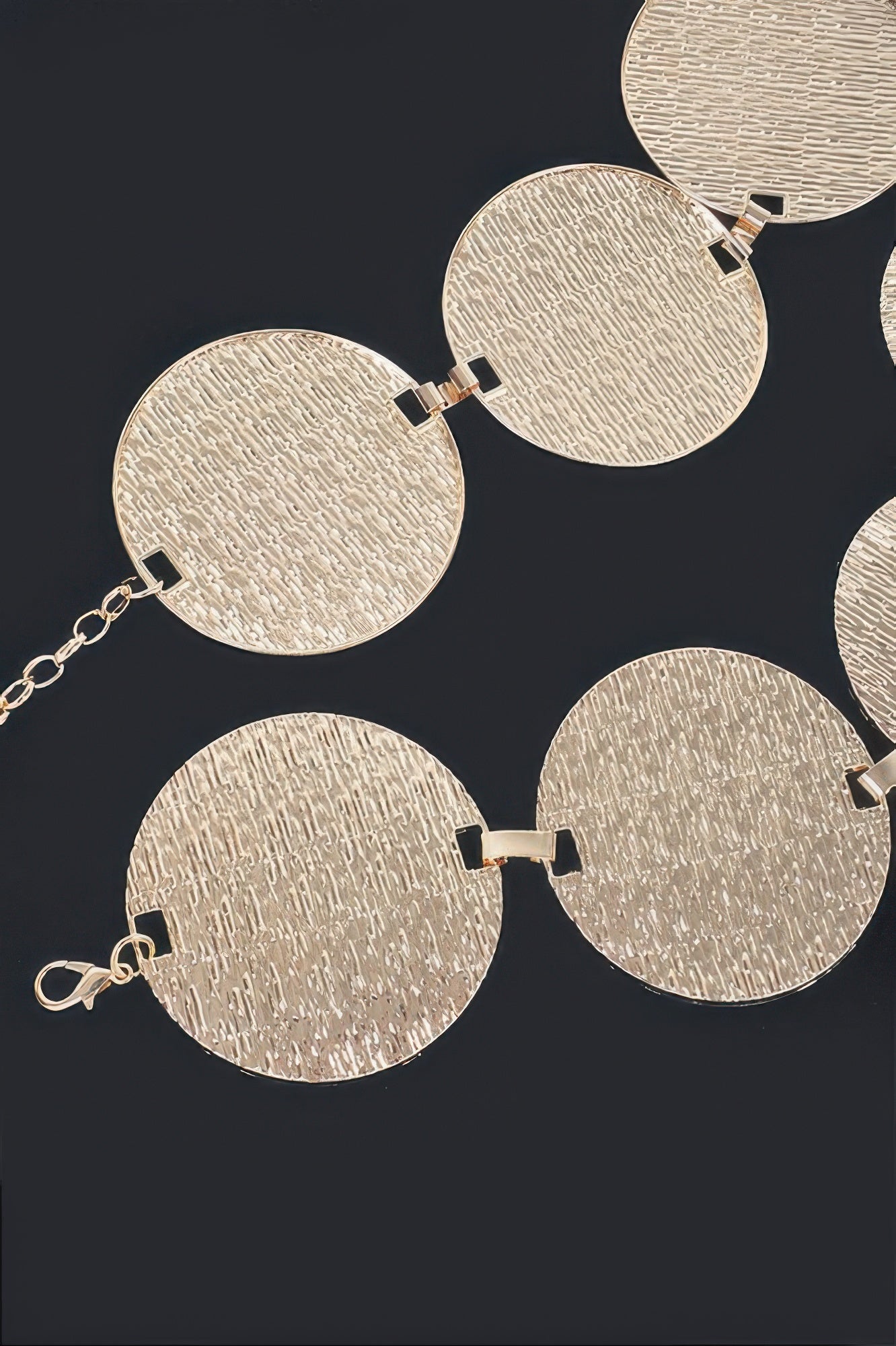 Close-up of gold circular plated belt: textured discs, snap clasps, chain