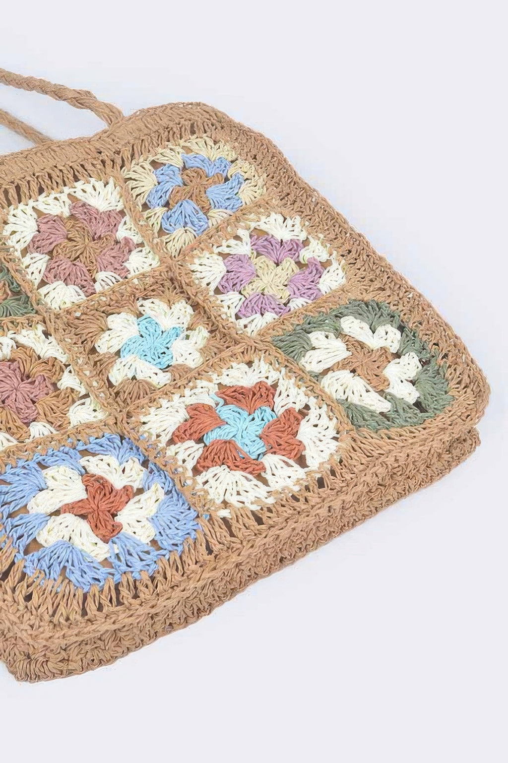 Multicolor crocheted floral squares on a faux straw tote bag front panel