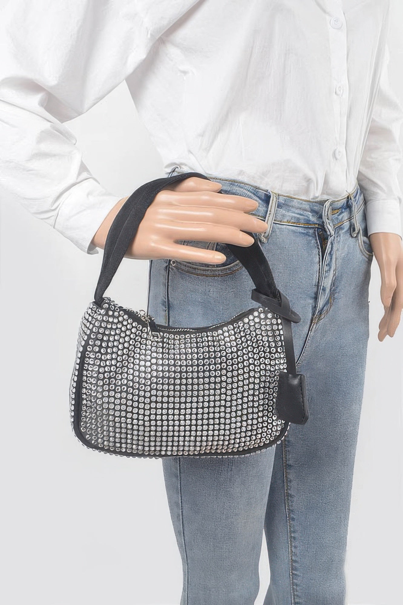 Black rhinestone shoulder bag held in front view with zip top and handle