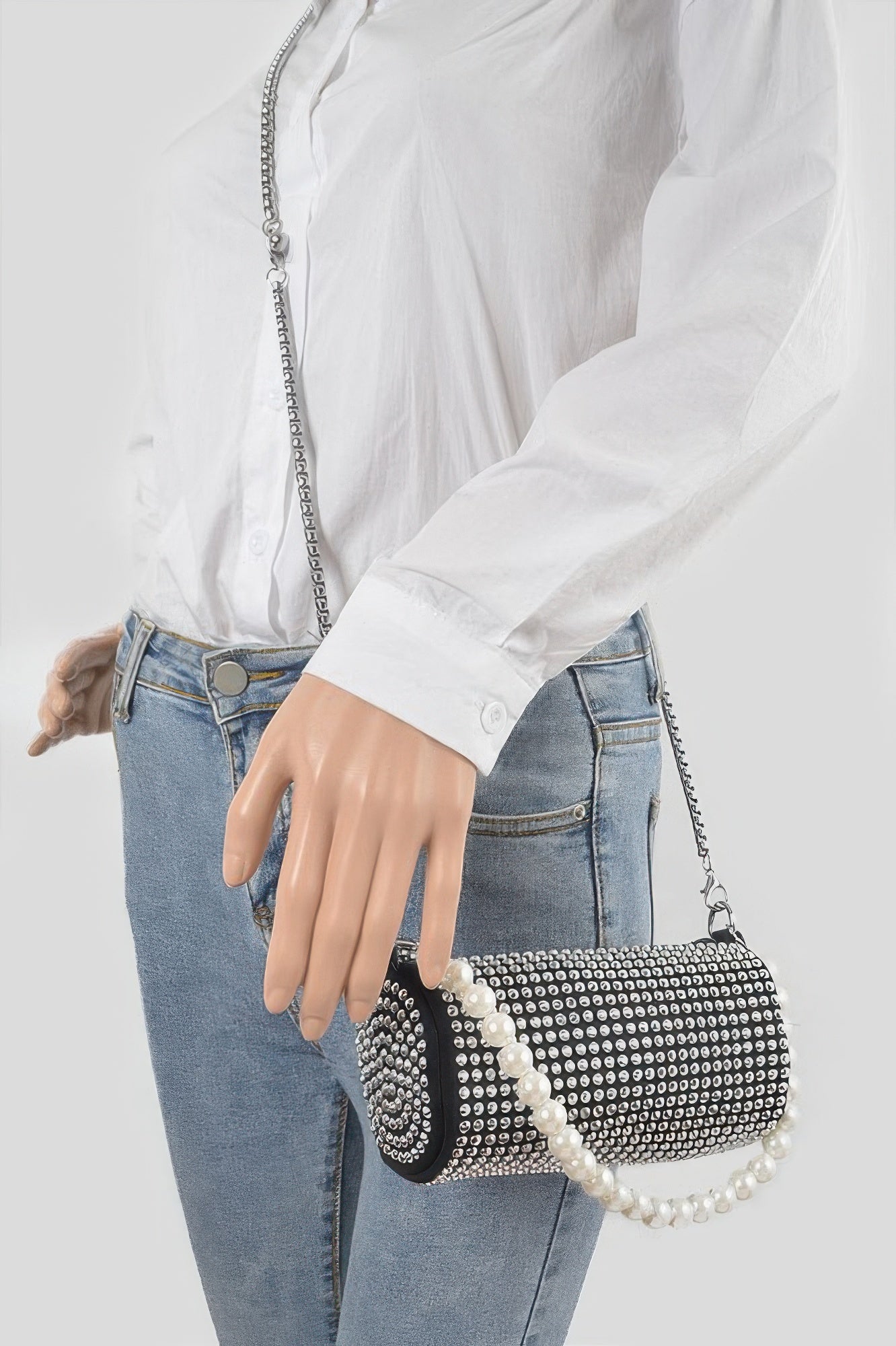 Black rhinestone tube bag worn on shoulder with pearl handle and silver chain strap.