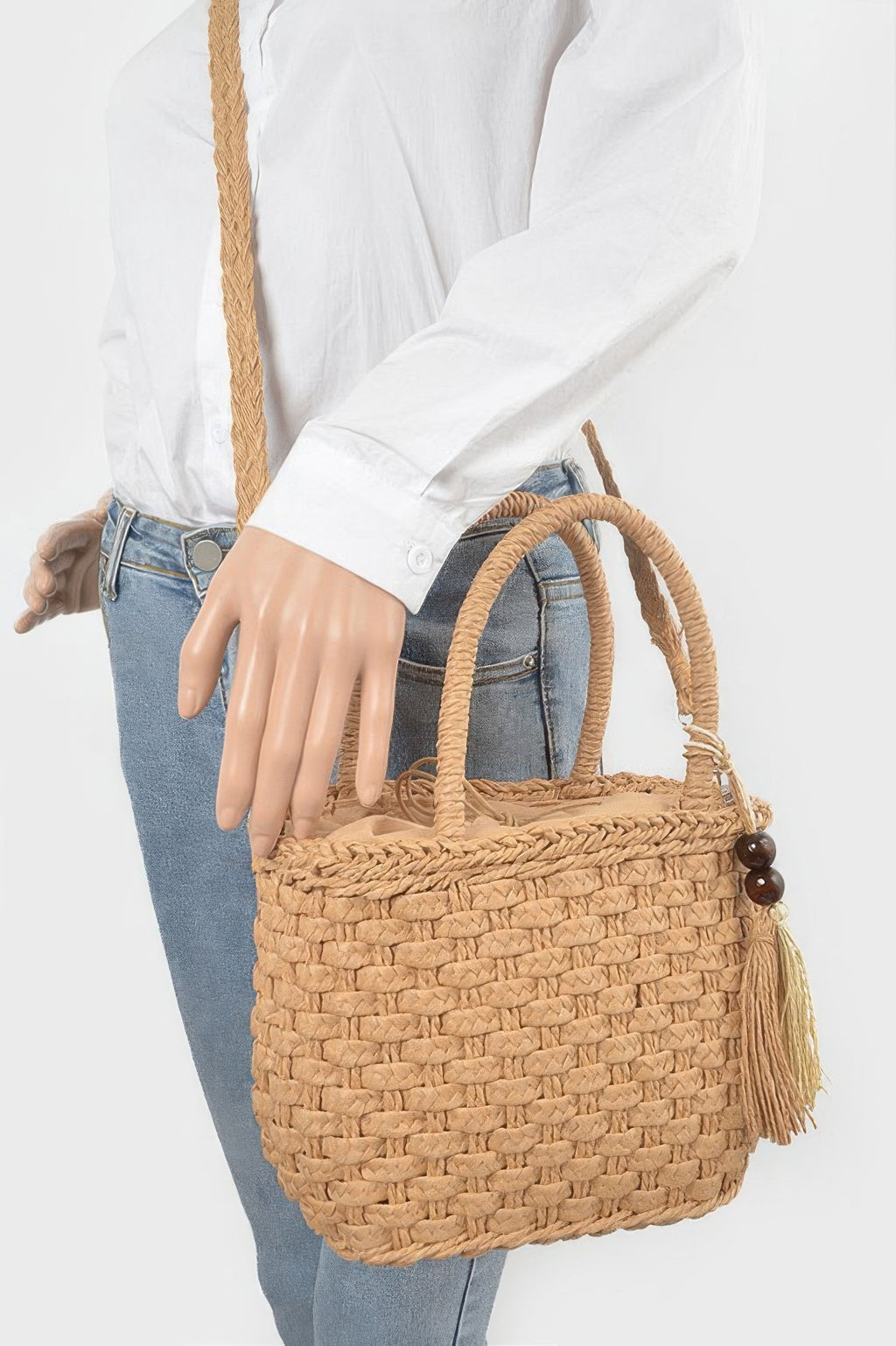Woven faux straw tote bag in khaki, worn on shoulder with long strap and tassel accent