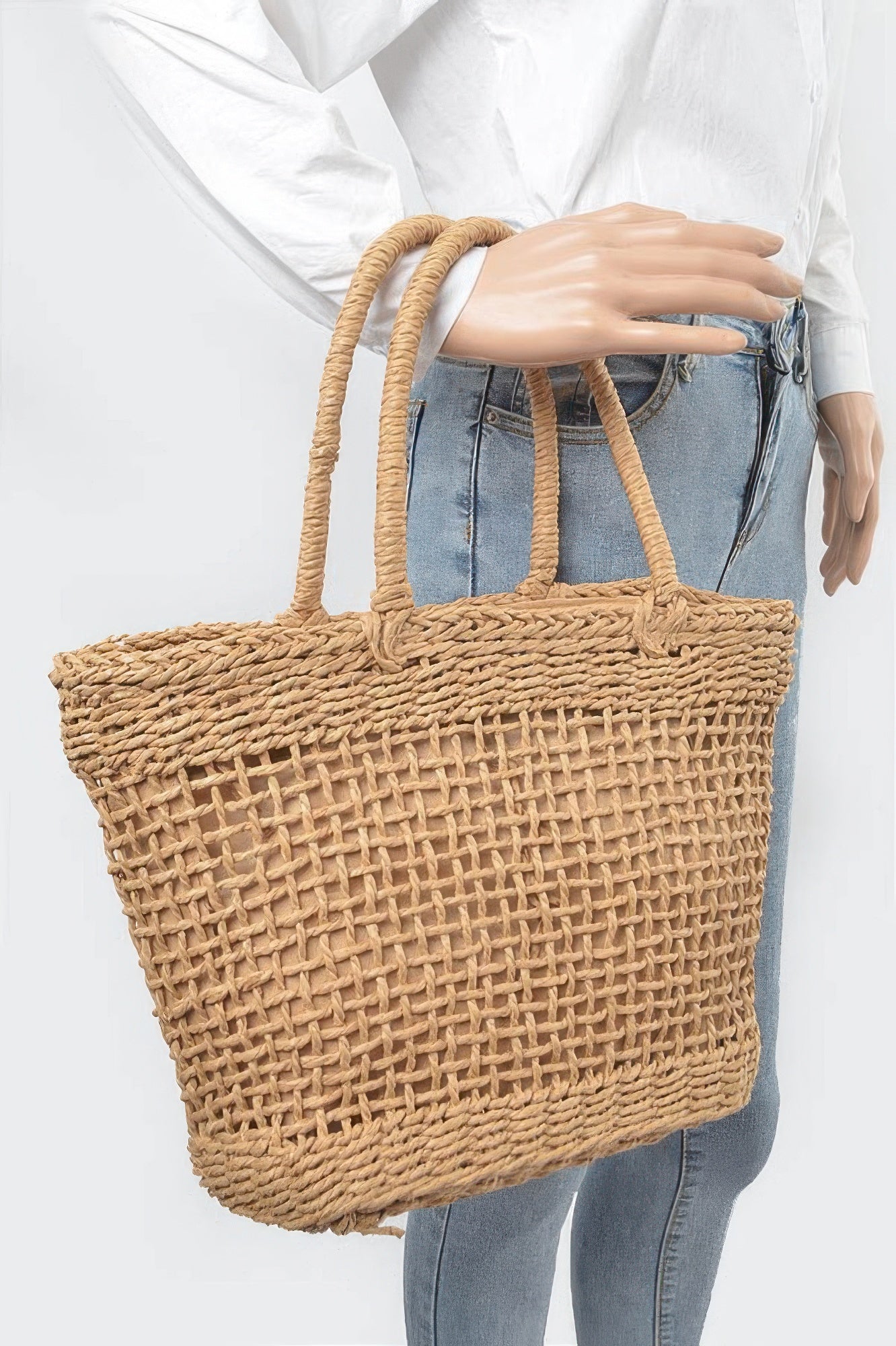 Khaki woven tote bag held by person, rope handles and open basket front.