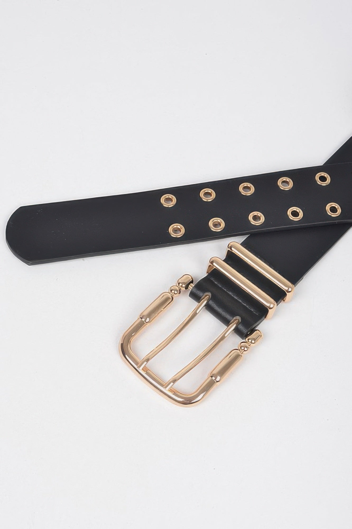 Black faux leather belt close-up: gold buckle with eyelet-studded strap
