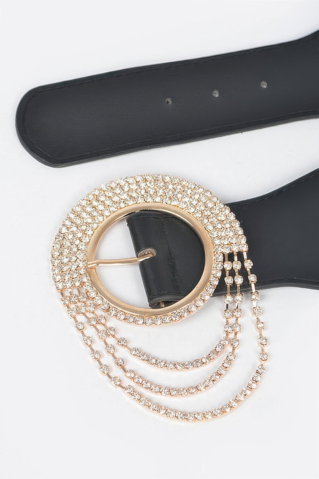 Close-up: gold-toned rhinestone round buckle on black elastic belt with layered chains
