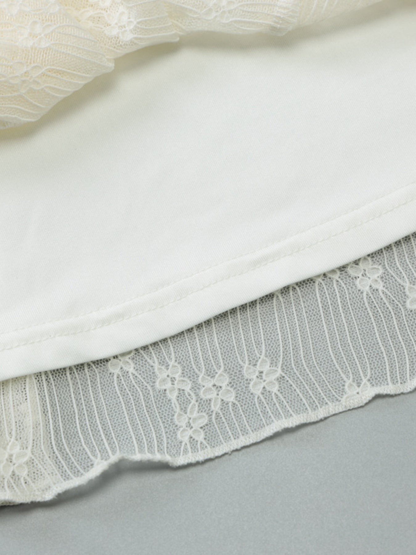 Cream mini dress close-up: textured lace hem and layered skirt