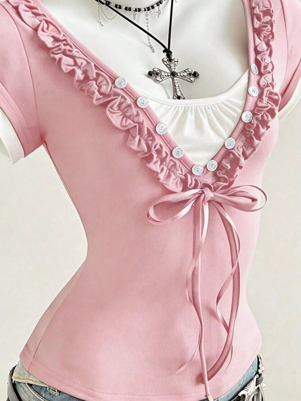 Pink T-shirt neckline with white ruffle, button placket, and bow-tie front