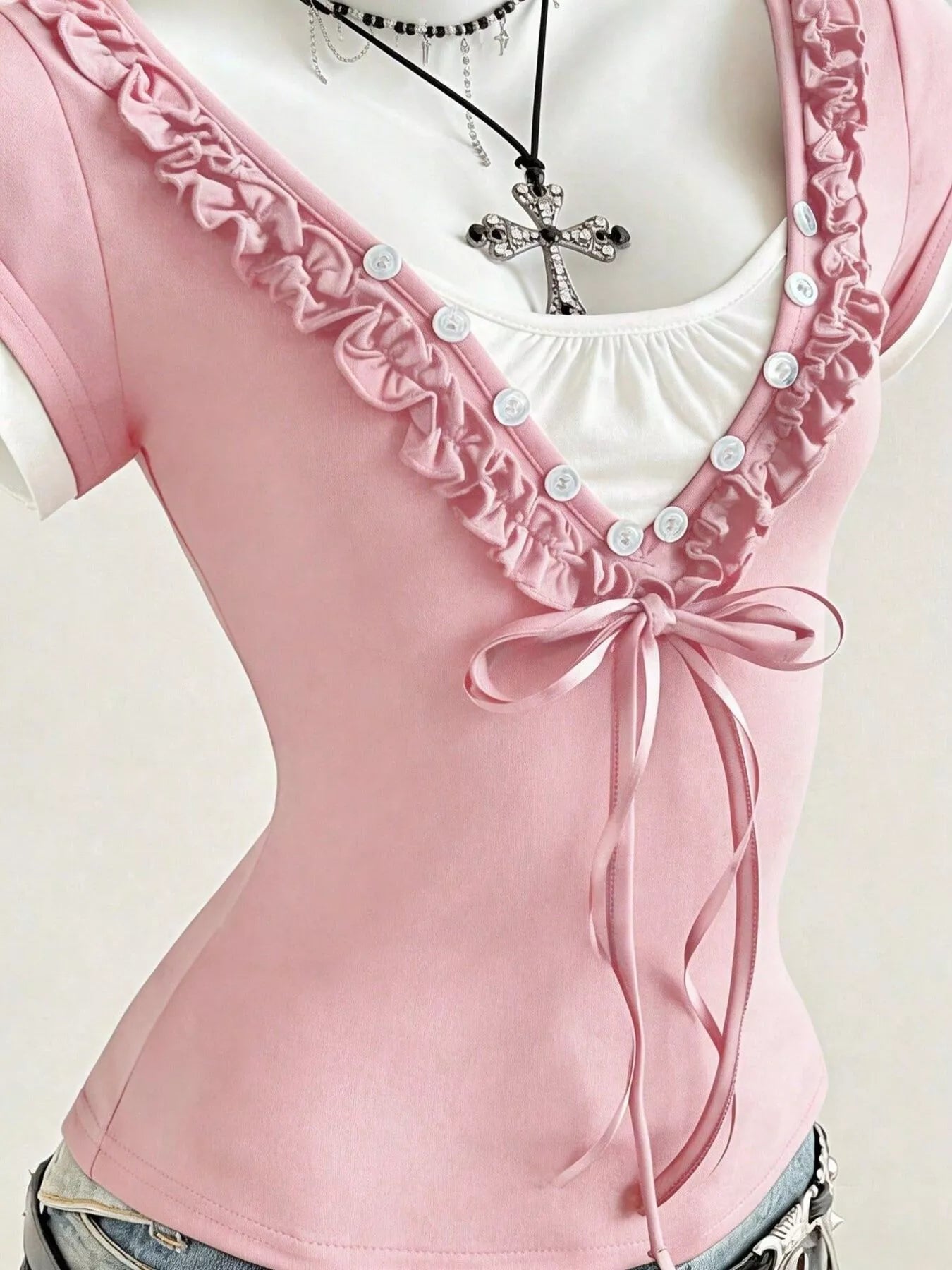 Pink T-shirt neckline with white ruffle, button placket, and bow-tie front