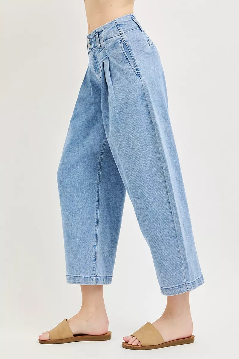 Medium-blue slouchy crop jeans in side profile, pleated barrel shape