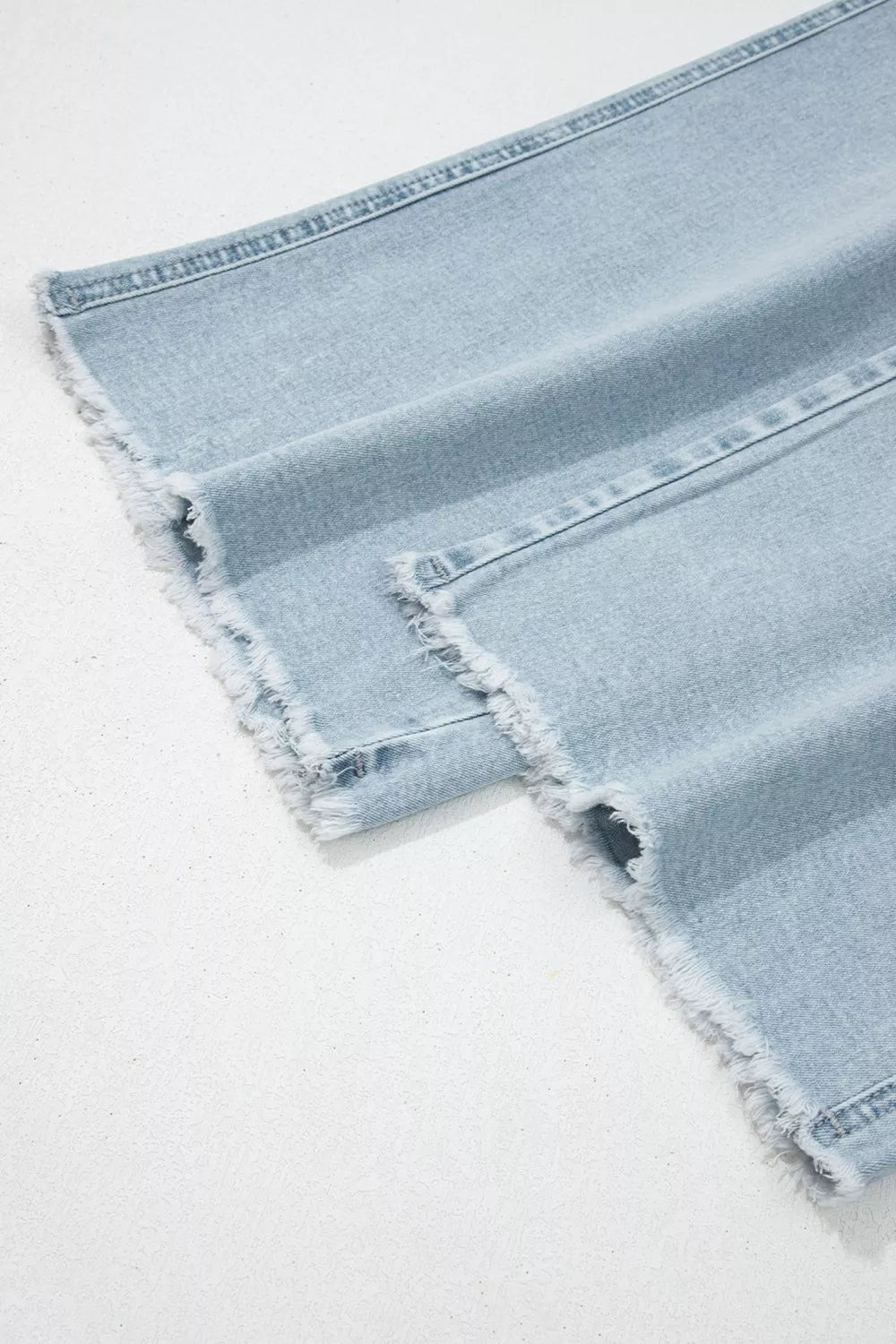 Frayed straight-leg jean hem in light wash denim with distressed edge finish
