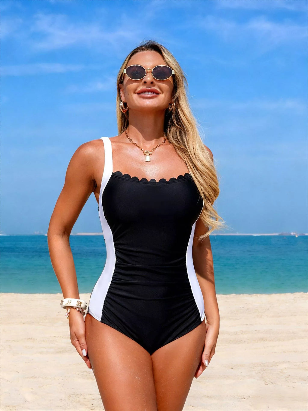 Black one-piece swimsuit with white vertical side panels, ruched waist and scalloped bust