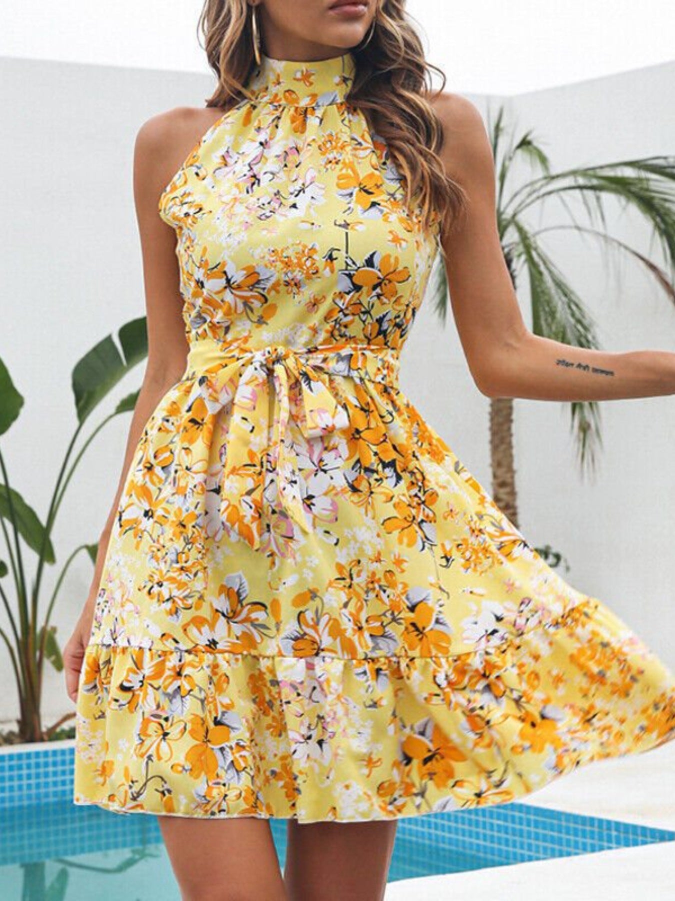 Pastel yellow floral halter neck mini dress with bow waist and layered tiers