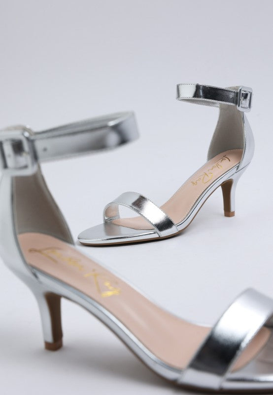 Close-up of metallic silver kitten heel sandals with ankle strap and open round toe