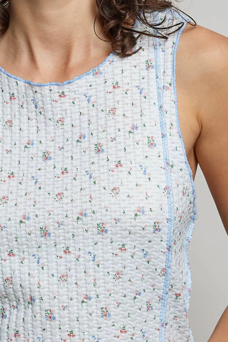 Close-up: light blue ribbed tank with round neck; micro-floral speckled print, blue trim