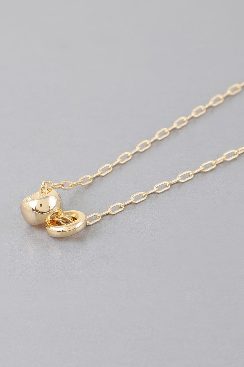 Gold-tone chain necklace with heart-shaped charm and side clasp detail