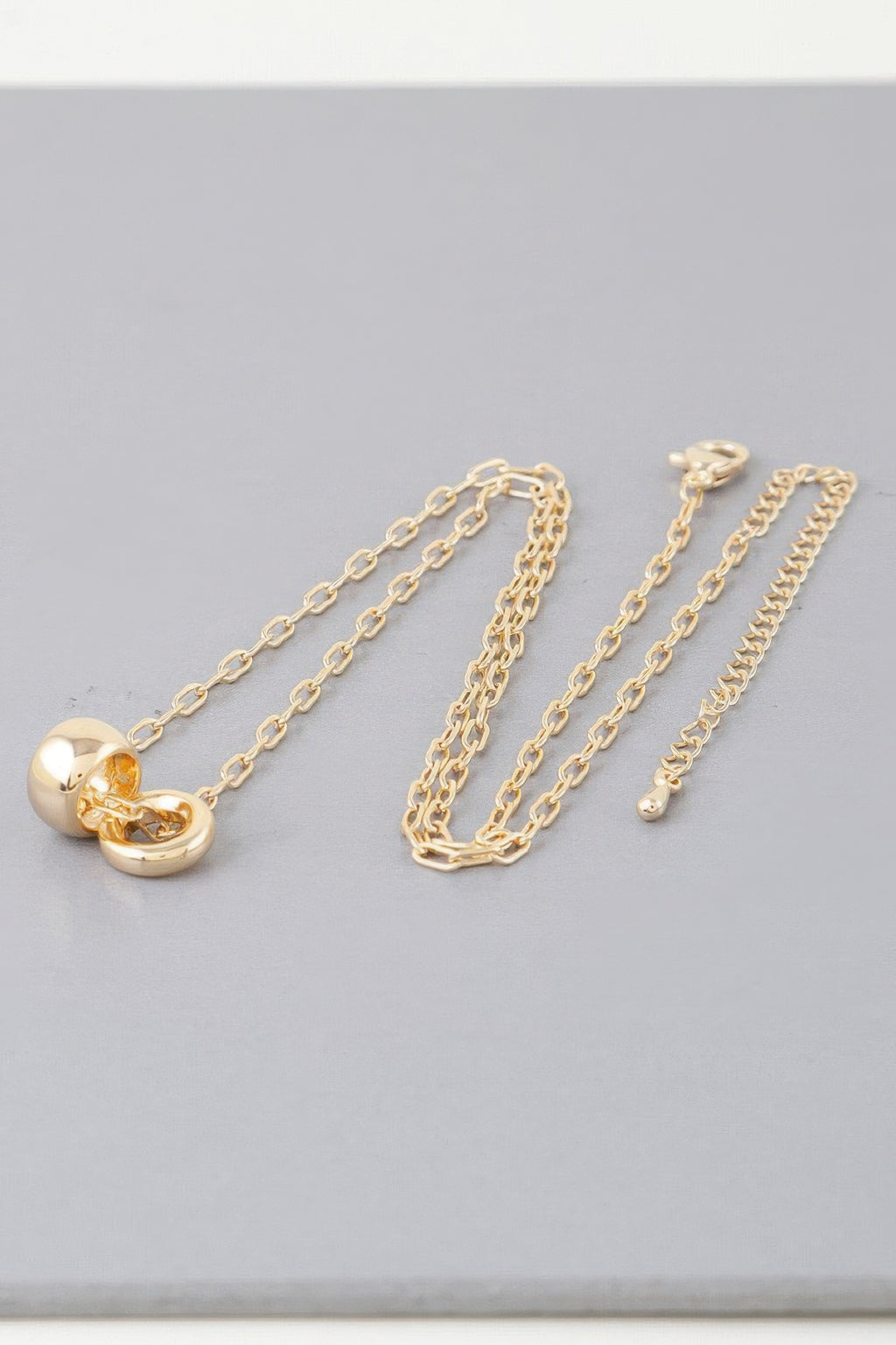 Gold-tone link chain necklace with heart charm; multiple chain strands shown