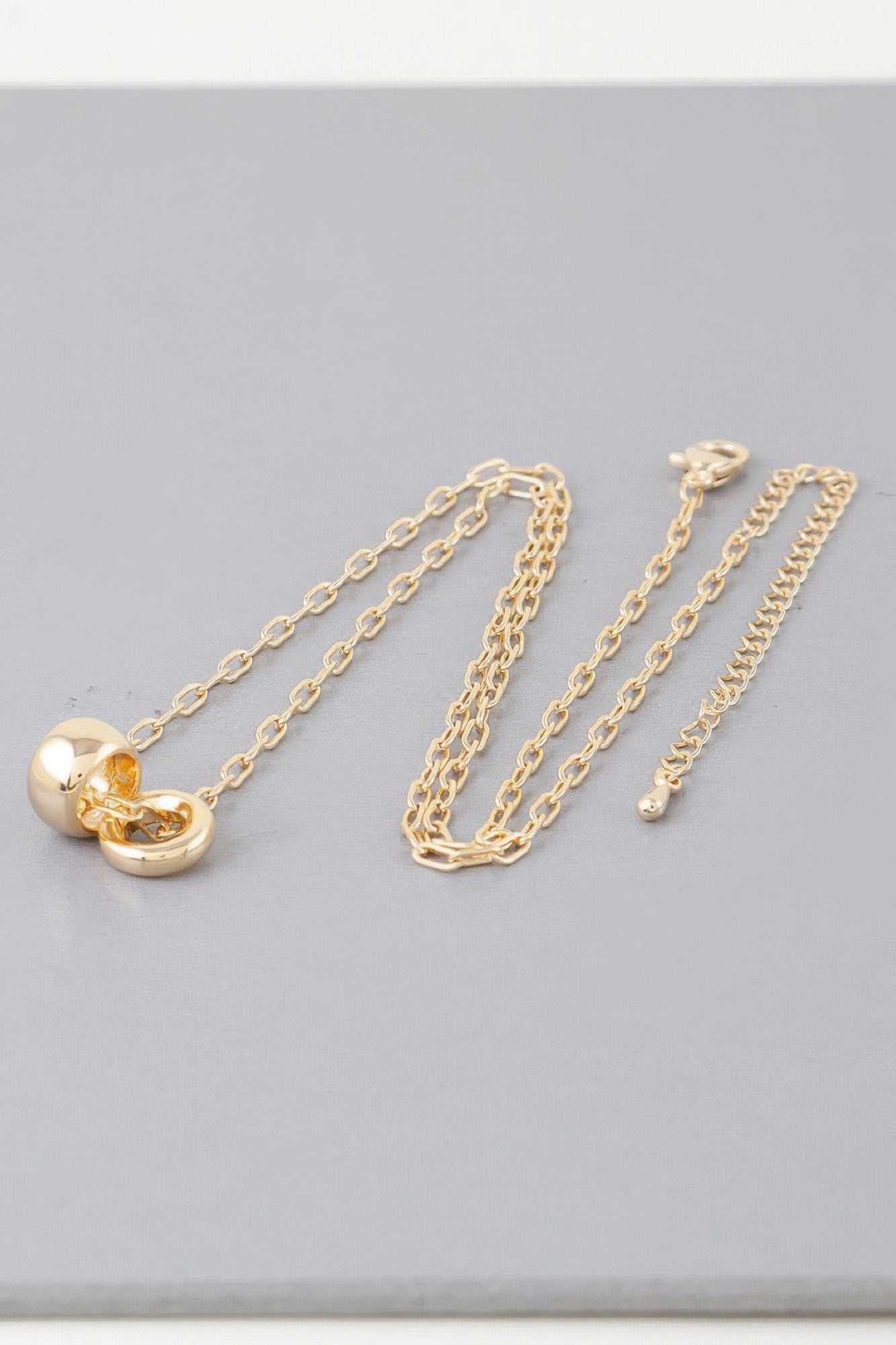 Gold-tone link chain necklace with heart charm; multiple chain strands shown