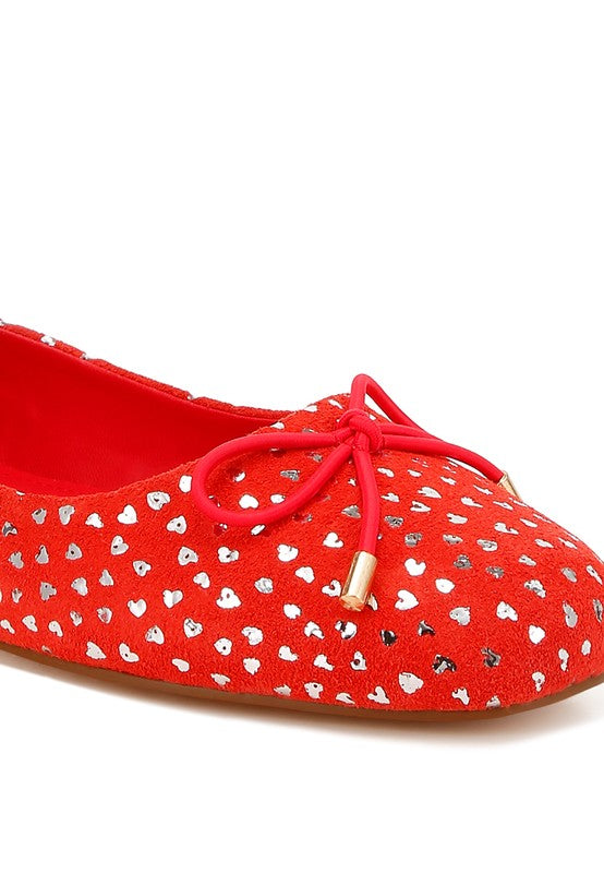 Close-up of red suede ballerina flats with bow detail and shiny speckle print