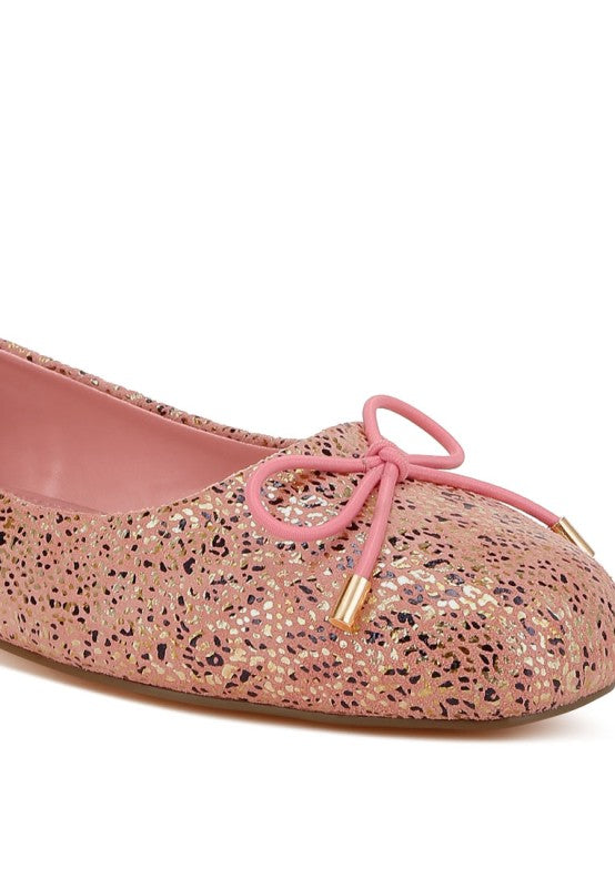 Close-up of pink suede ballerina flats with bow detail and shiny speckle foil print