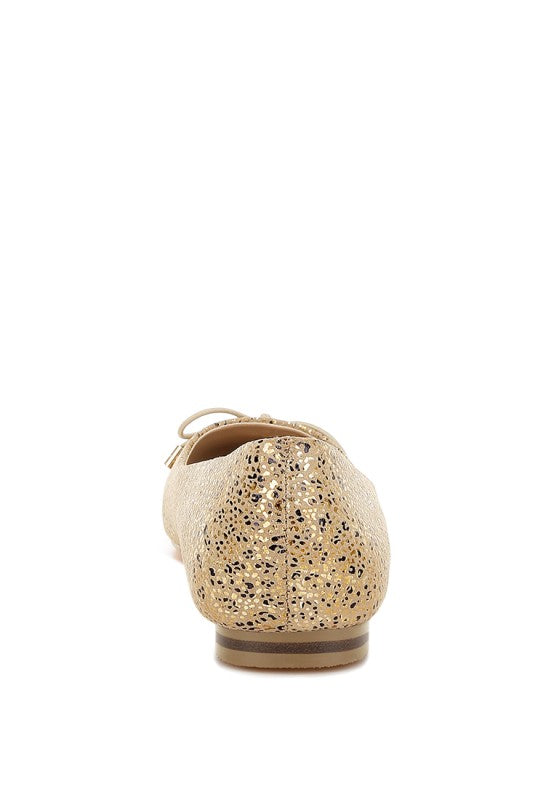 Back view of gold suede ballerina flats with foil speckle print and bow
