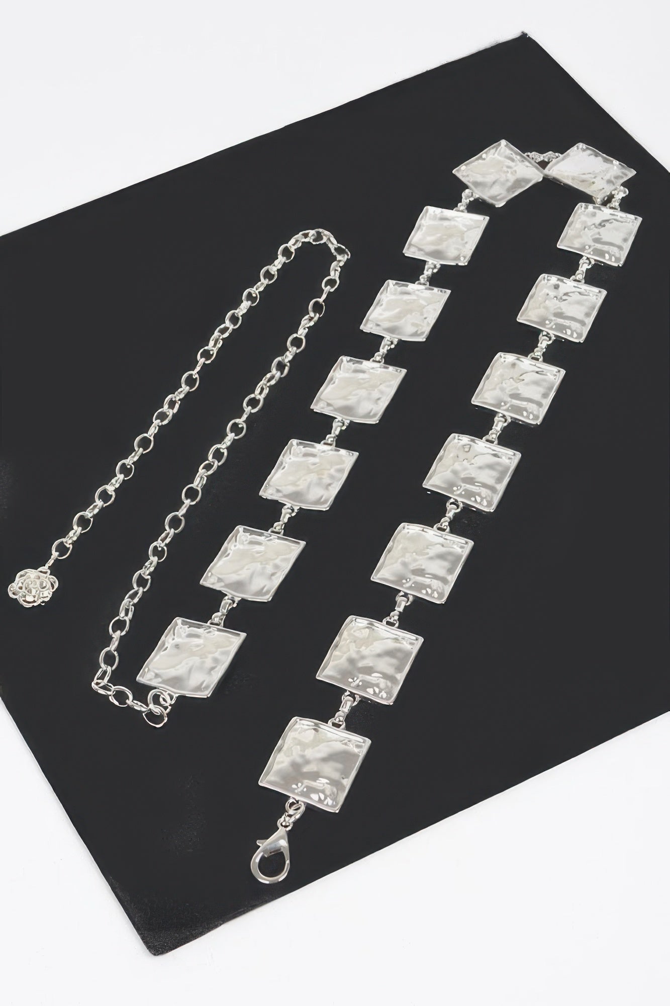 Silver hammered square chain belt set on flat surface, square-link rows and clasp