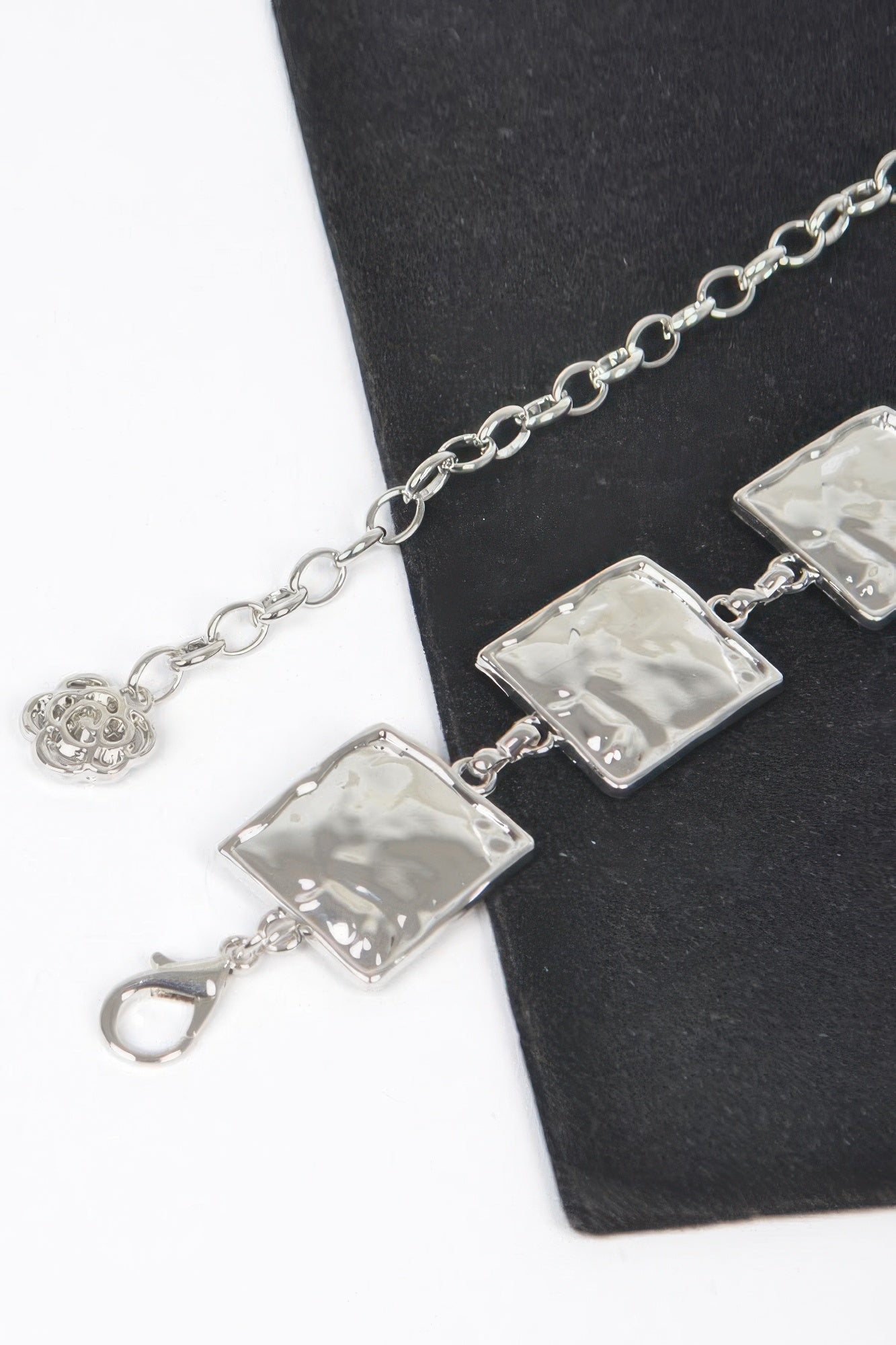 Close-up of silver hammered square chain belt links and round clasp charm