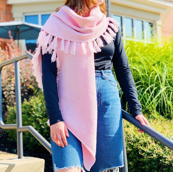 Pink fringed blanket scarf with long ends and tassels along the edge