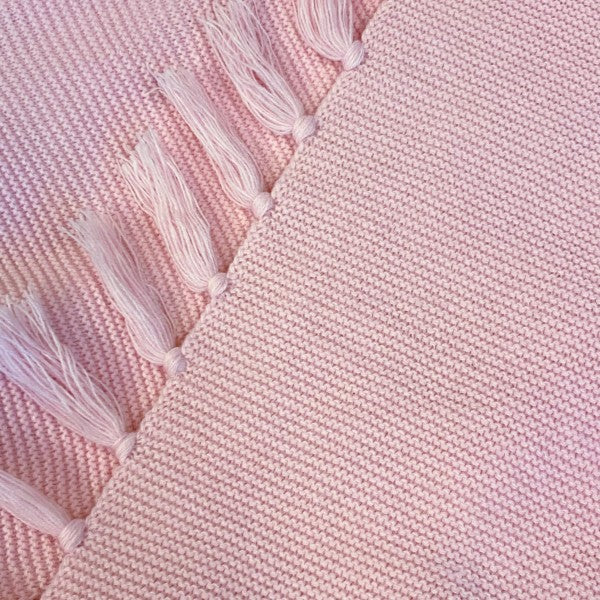 Close-up of pink knitted blanket scarf with fringe tassels and textured weave