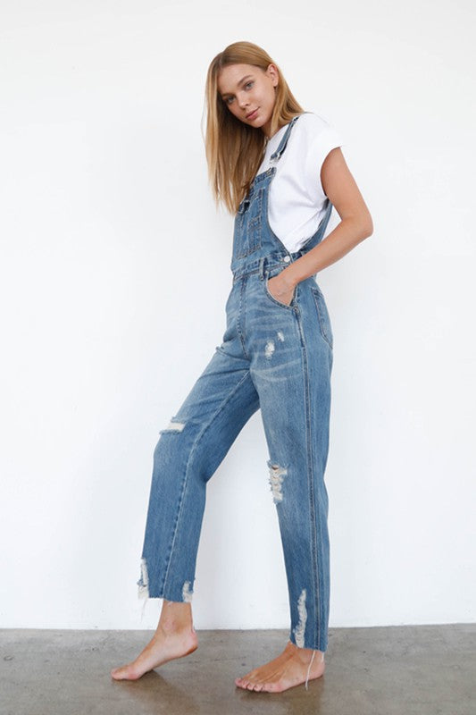 Medium-wash ripped denim overall jumpsuit, straight-leg fit with front bib and tears.