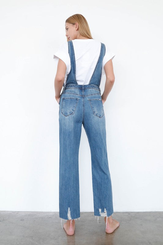 Ripped denim overall jumpsuit, high waist; back view with straight wide legs.