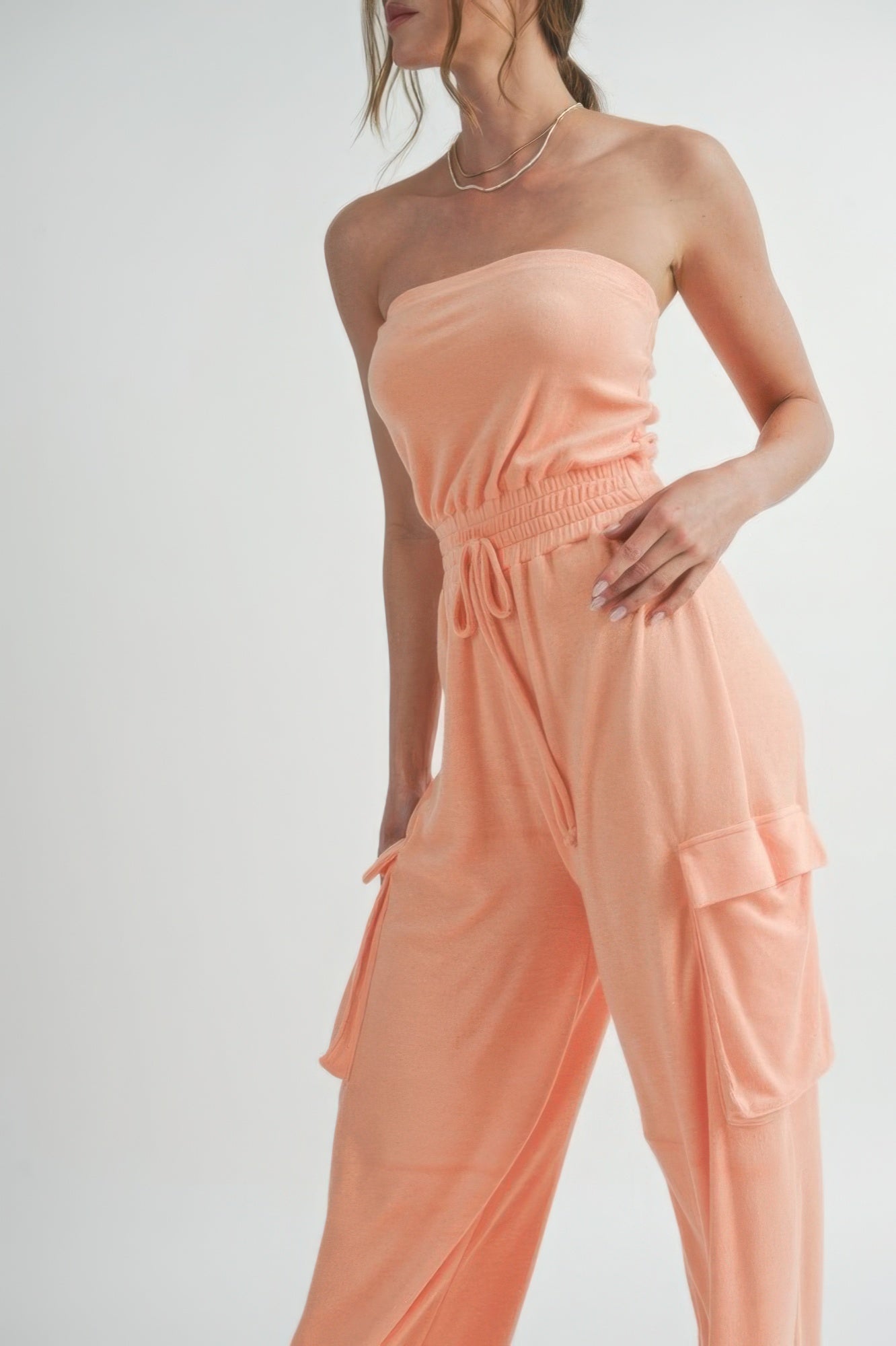 Peach strapless tube top jumpsuit with elastic waist ruching and cargo pocket on leg