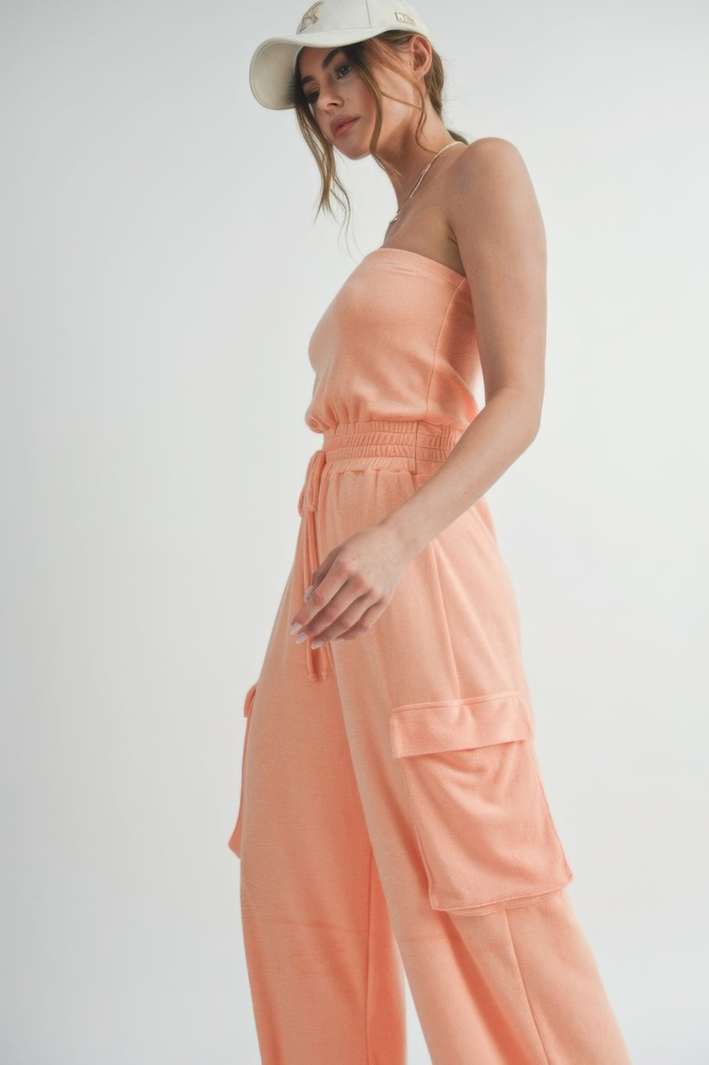 Peach tube top jumpsuit side view with drawstring waist and layered cargo pocket details