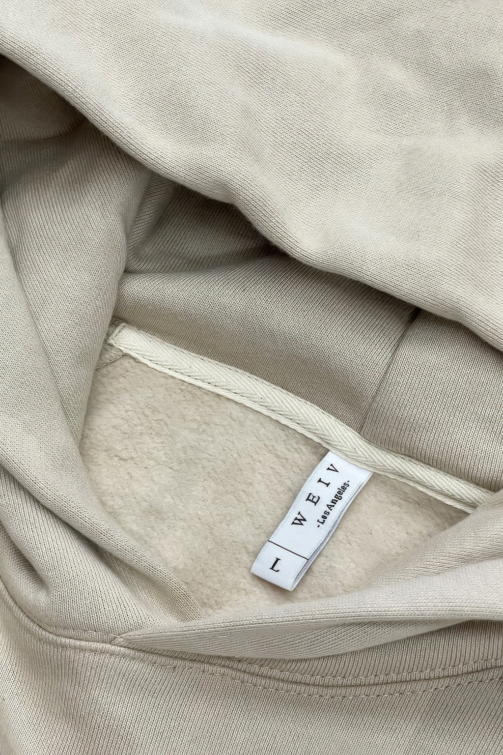 Oatmeal hoodie fabric close-up with inner neck label
