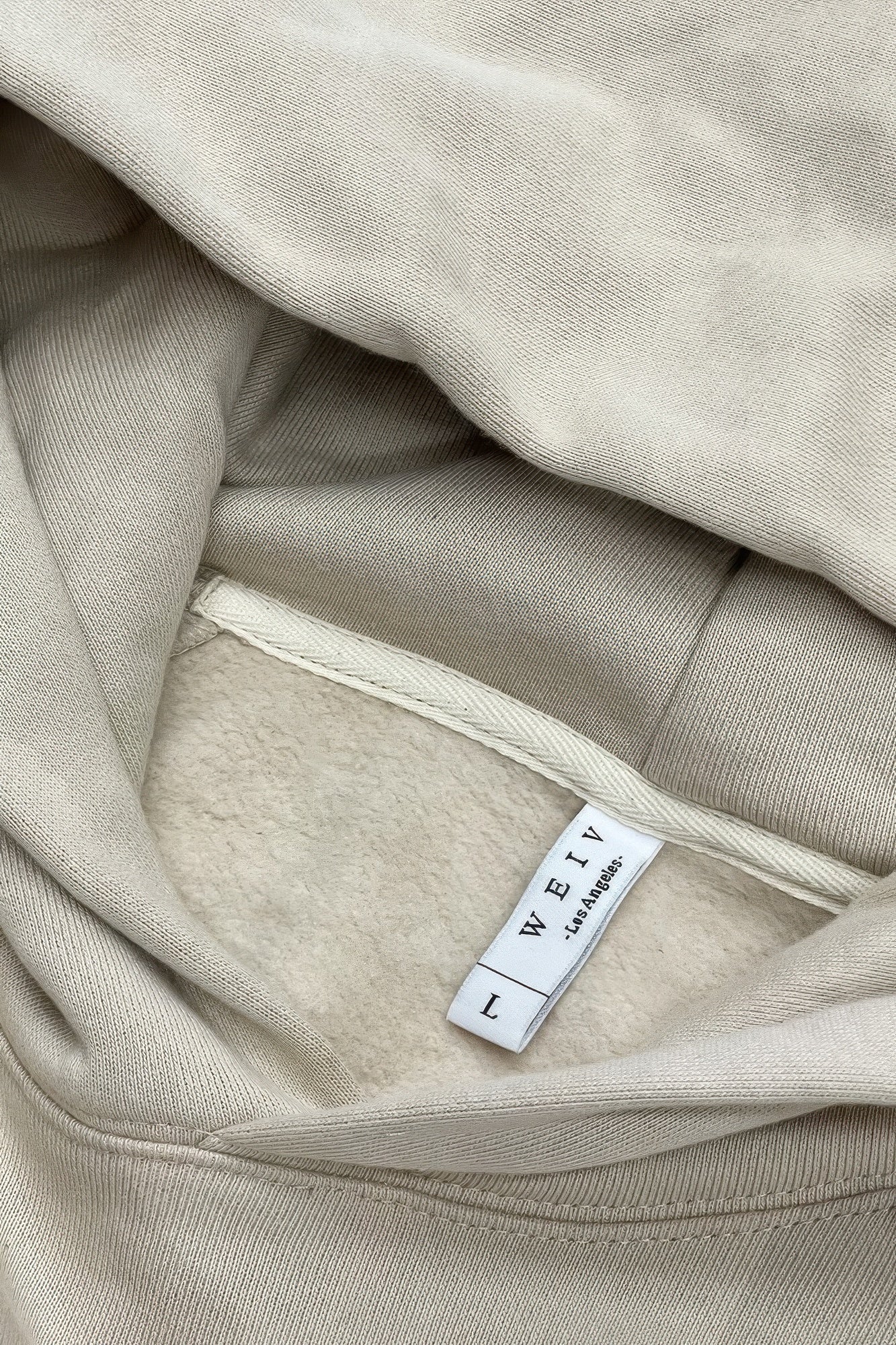 Oatmeal hoodie fabric close-up with inner neck label