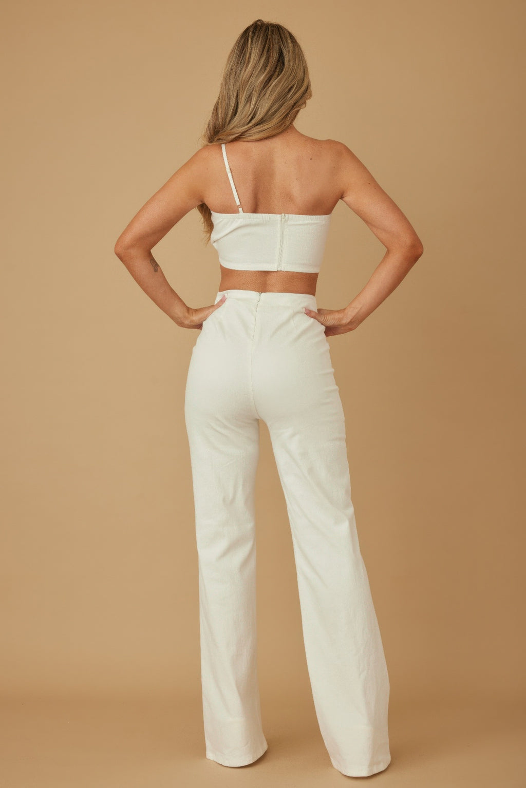 Rückansicht: weißes Crop-Top mit dünnem Trägerdetail und ausgestellte Hose
