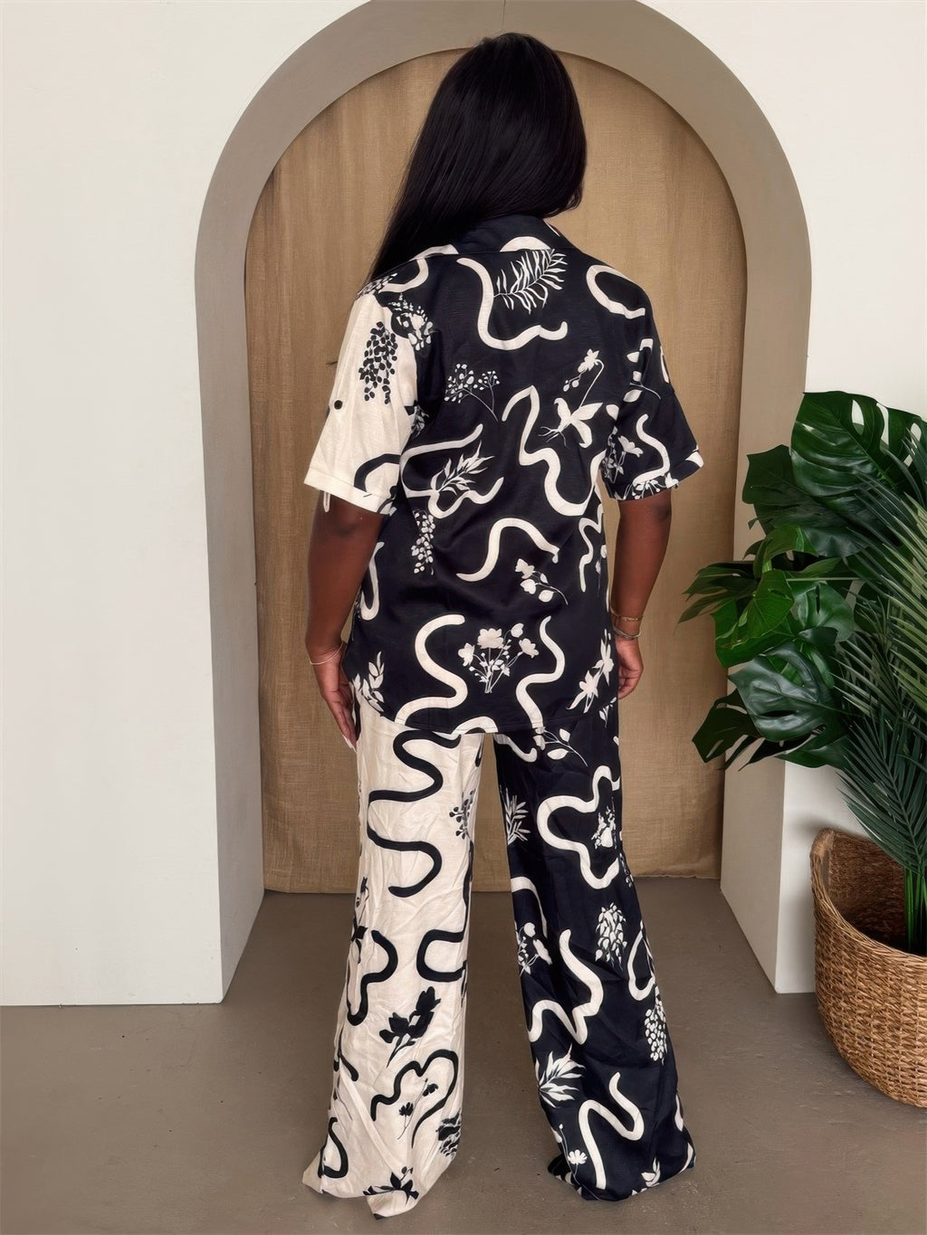 Back view of black/white abstract resort pant set: short-sleeve shirt and wide-leg trousers