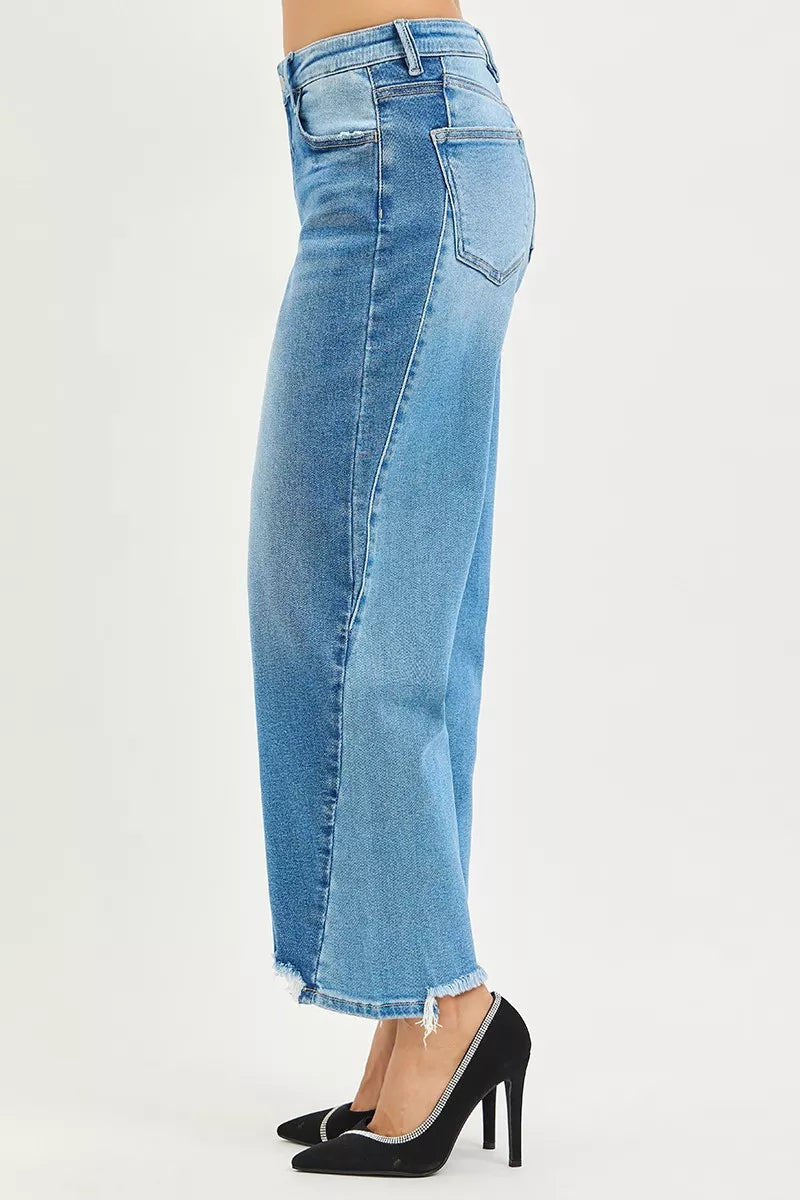 Side view of light blue wash jeans with stitched seams, back yoke, and frayed hem