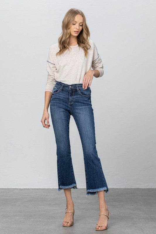Dark blue mid-rise bootcut jeans, frayed cuffs at the cropped ankle