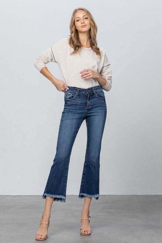Dark blue bootcut crop jeans with frayed raw hem along both leg openings