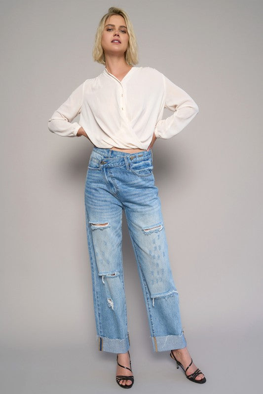 High-waist crossover ripped straight jeans, medium wash, with multiple ripped areas on legs.