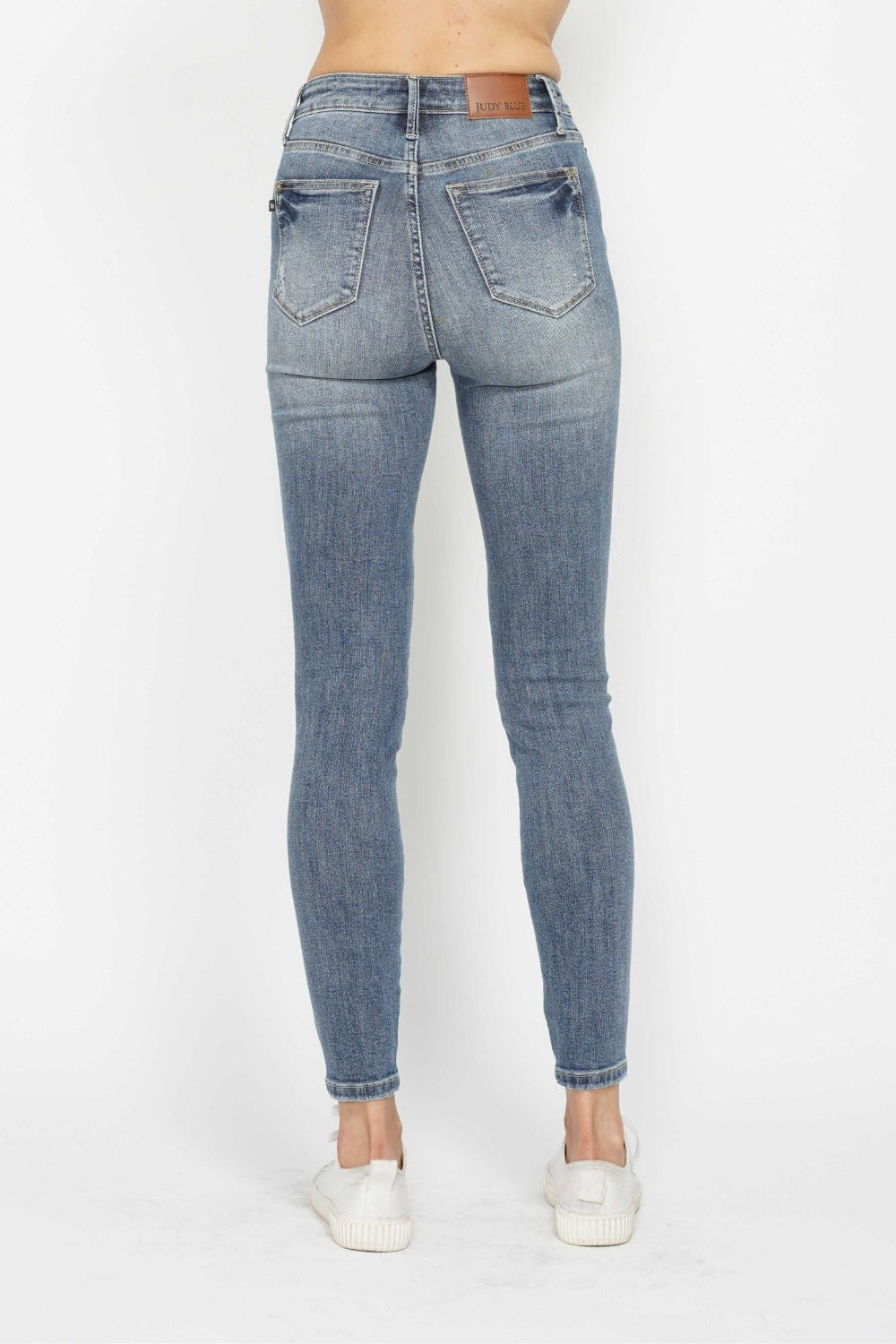 Medium wash skinny jeans, back view with two rear pockets and button closure