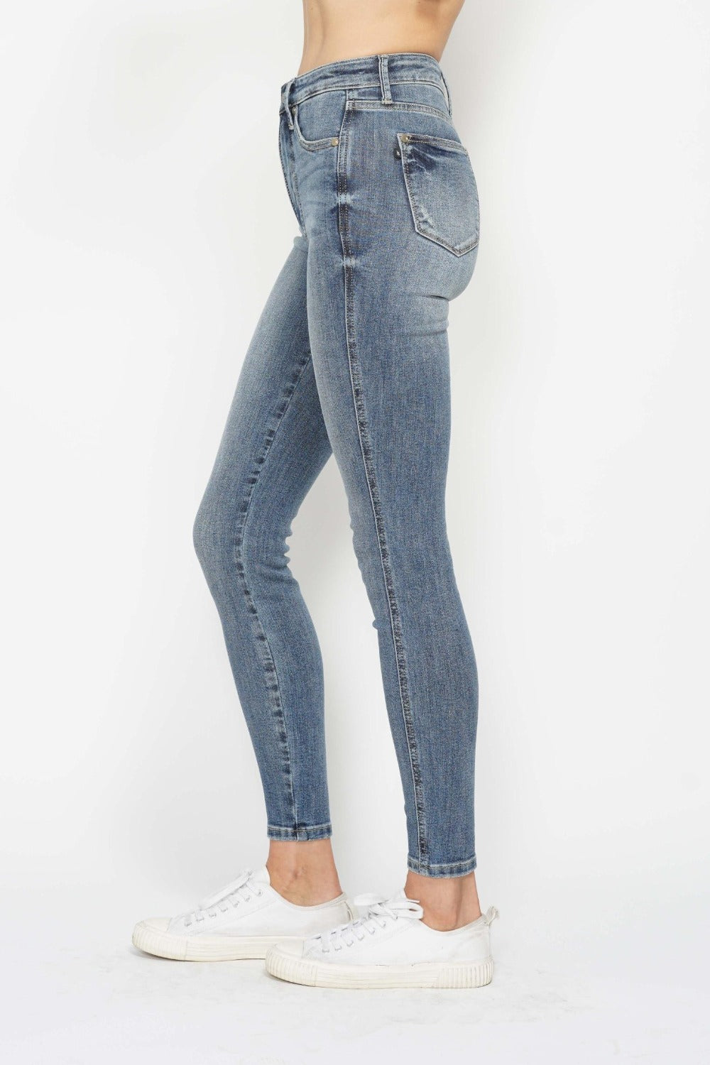 Medium wash skinny jeans, back-side view with fitted legs and ankle hem