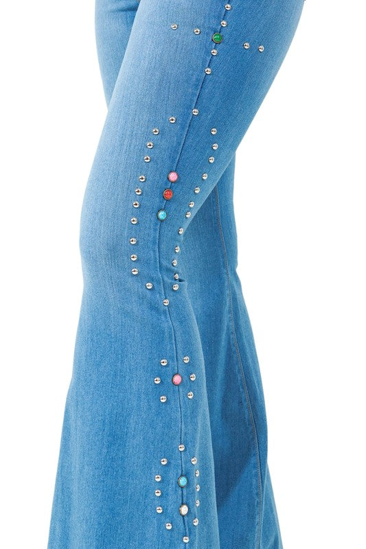 Medium-wash bell-bottom jeans close-up: vertical rows of rhinestone and bead studs.