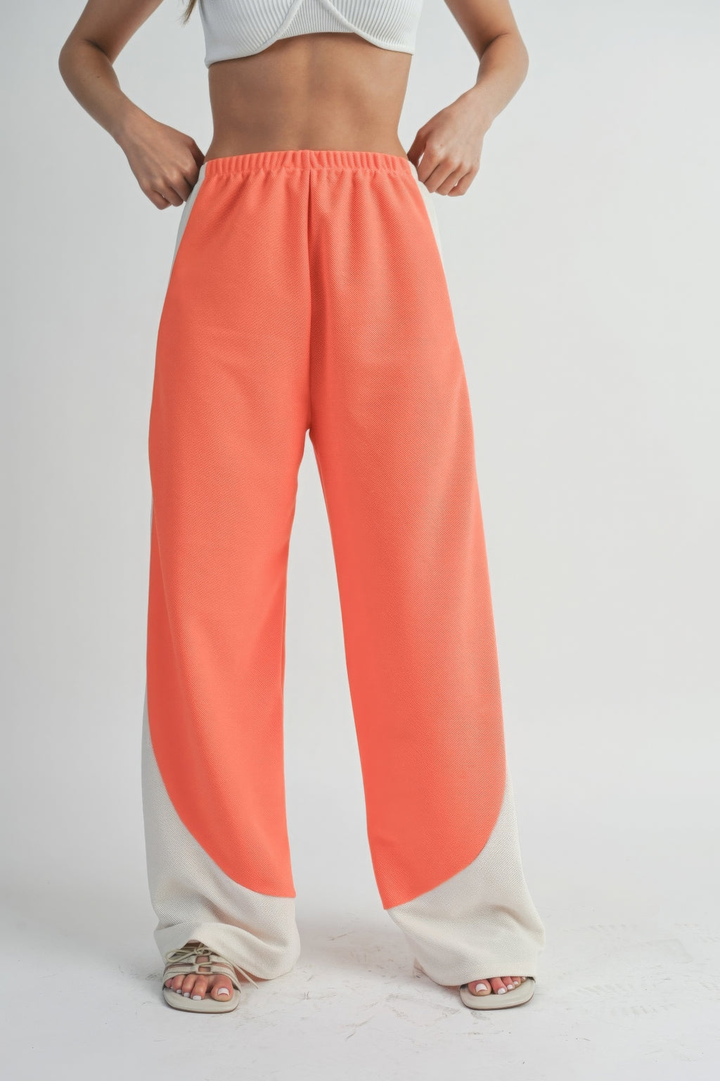Wide-leg pants with coral center and light side panels, relaxed drape from elastic waist.