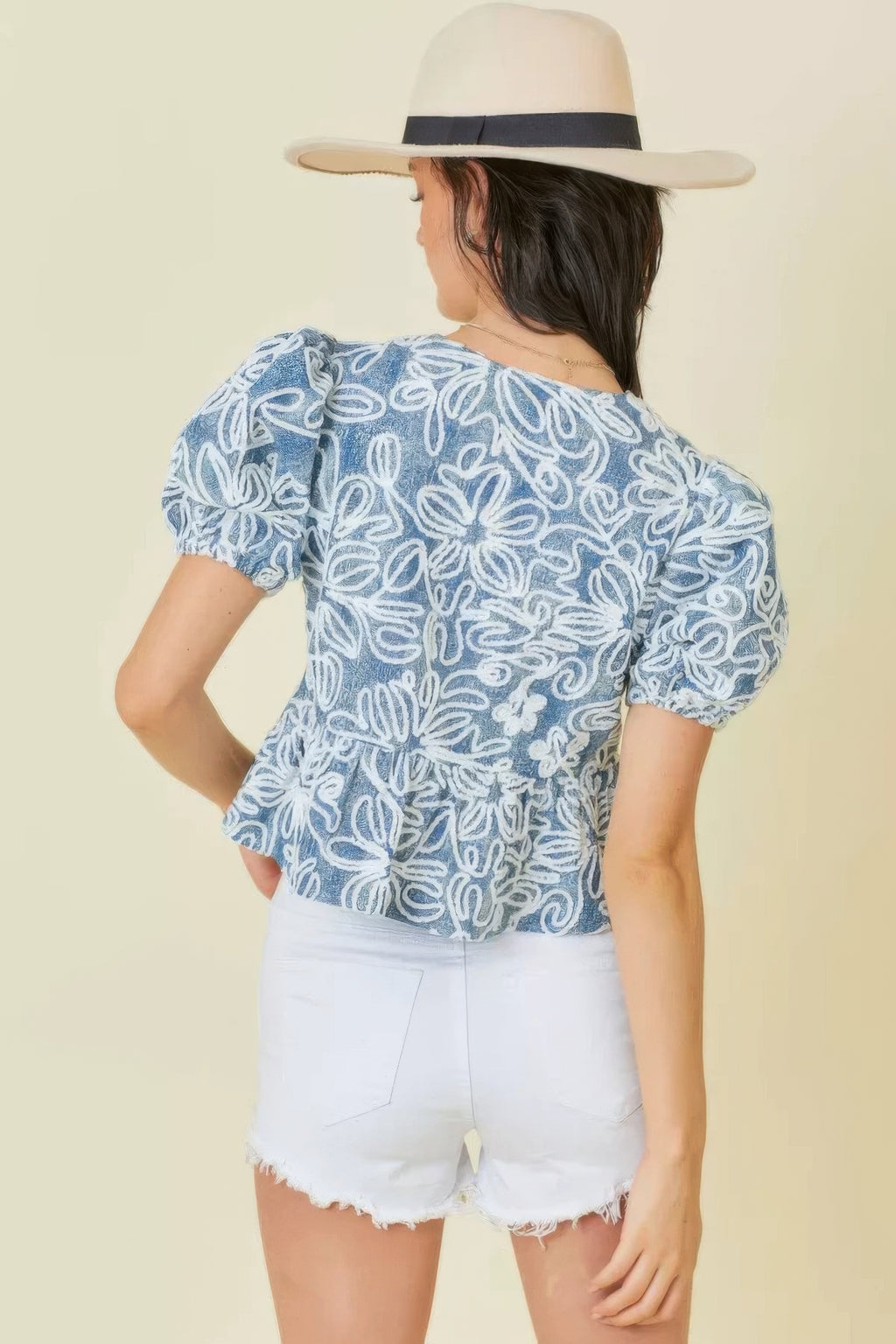 Blue/white embroidered crop top from back view with puff sleeves and peplum hem