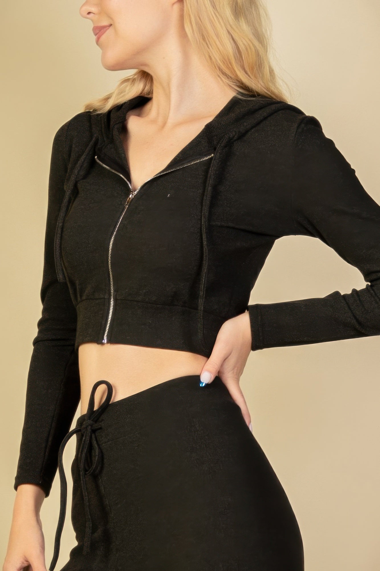 Black zip-up cropped hoodie close-up with front zipper and hood drawstrings